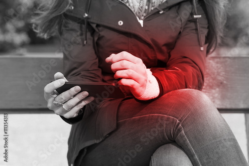 Woman with a injured wrist using a smartphone feeling pain.