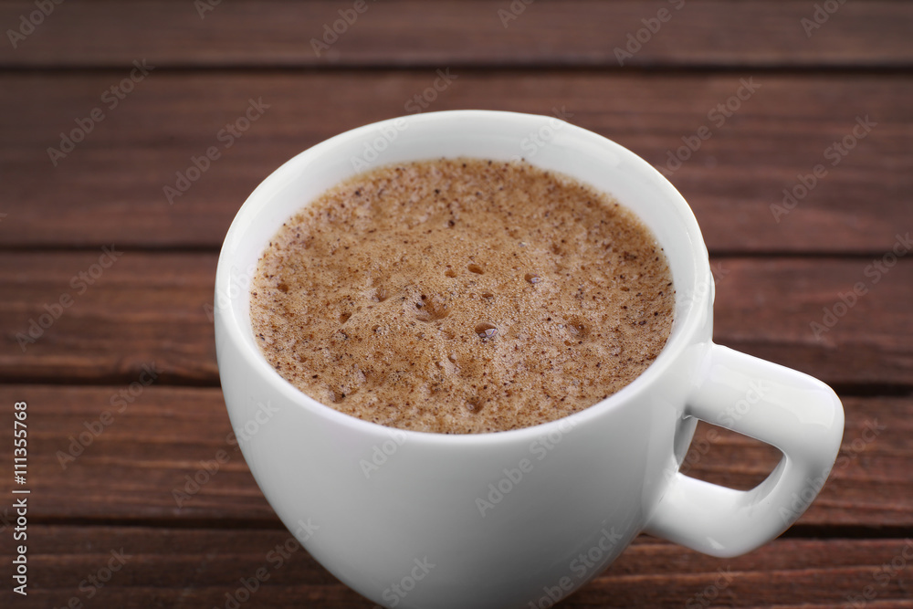 Cup of coffee with brown foam on wooden background Cup of coffee with brown foam on wooden background