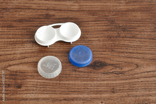 A holder for contact lenses isolated on a wooden background
