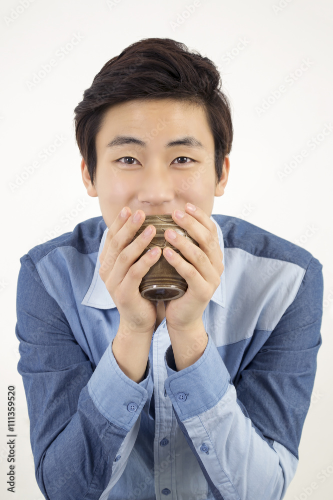 Asian young handsome man holding a ceramic cup of tea Asian young handsome man holding a ceramic cup of tea