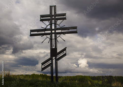 памятный христианский крест на фоне неба и травы