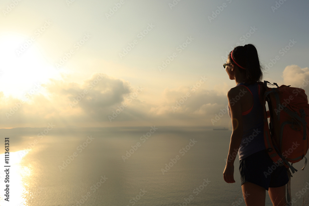  young woman backpacker enjoy the view at sunrise seaside mountain peak