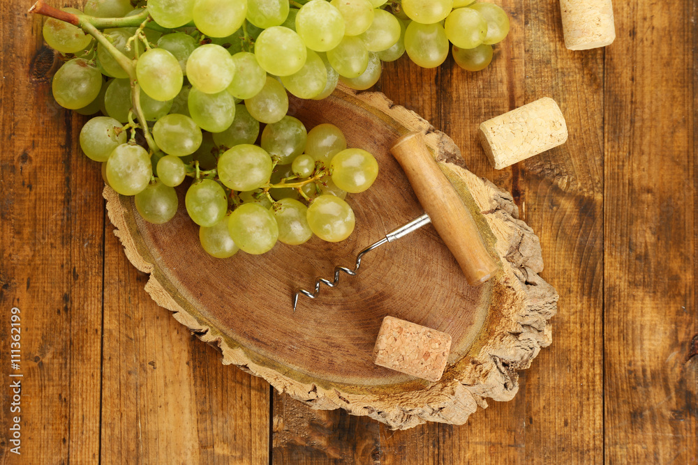Wine corks and tailspin with bunch of grapes on wooden background Wine corks and tailspin with bunch of grapes on wooden background