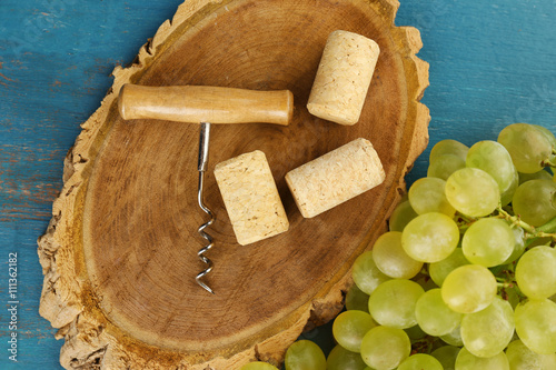 Wine corks and tailspin with bunch of grapes on wooden background photo