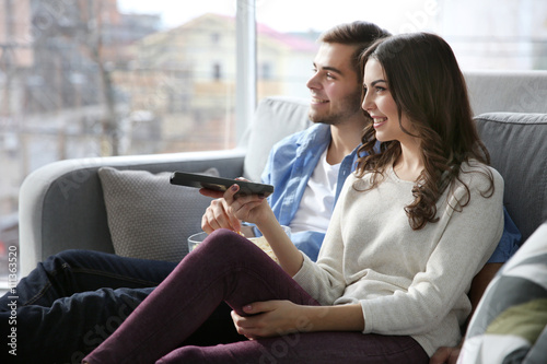 Young couple watching TV on a sofa at home