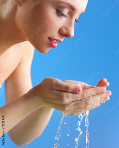 Young female washing her face with clear water