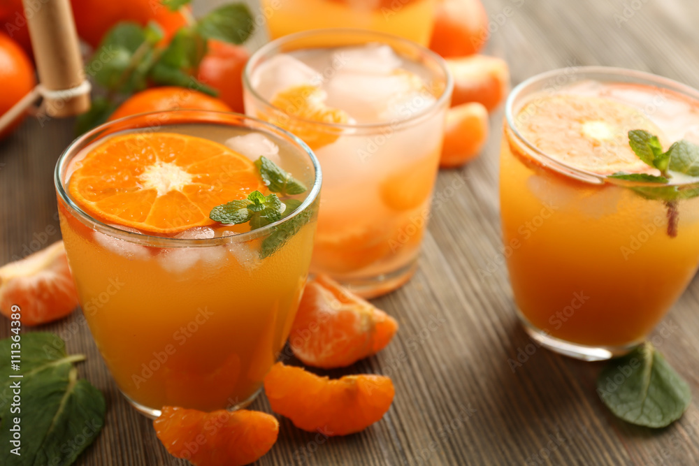 Tangerine cocktails with sliced mandarins, ice, mint on a wooden table, close up Tangerine cocktails with sliced mandarins, ice, mint on a wooden table, close up
