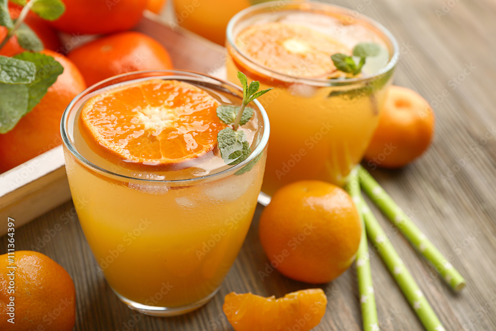 Delicious tangerine cocktails with ice, mint on a wooden table, close up Delicious tangerine cocktails with ice, mint on a wooden table, close up