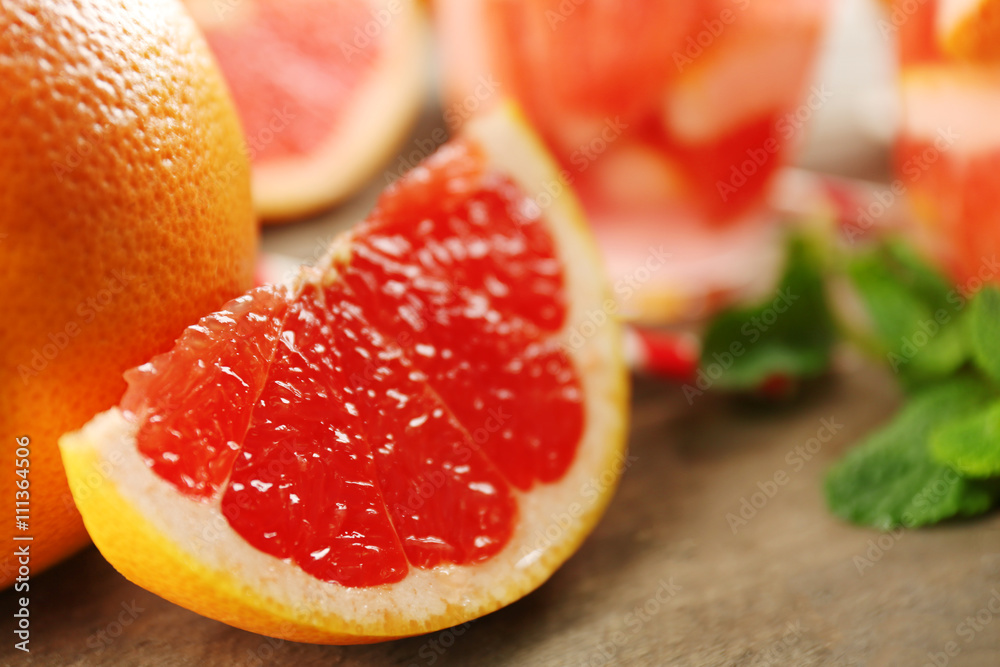 Juicy pieces of grapefruit with fresh mint on wooden table, close up Juicy pieces of grapefruit with fresh mint on wooden table, close up