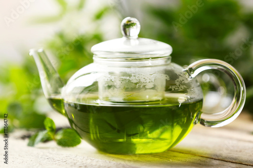 Teapot of green tea on wooden table