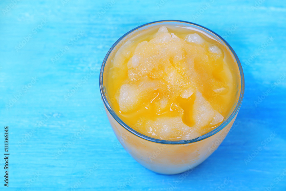 Glass of orange juice with crushed ice on blue wooden table Glass of orange juice with crushed ice on blue wooden table