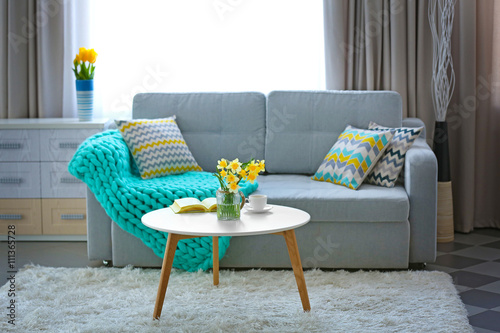 Yellow narcissus on white table in room interior