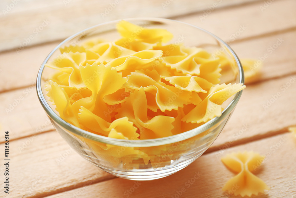 Pasta farfalle in bowl on wooden table background Pasta farfalle in bowl on wooden table background