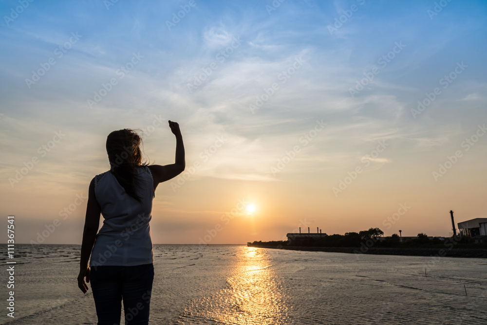 Fototapeta premium woman with arm raised up feeling success and strong on sunset background