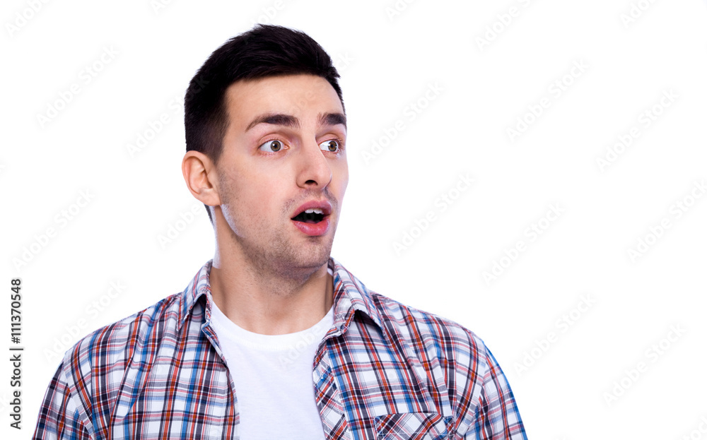 Shocking news. Portrait of surprised young man in casual shirt keeping mouth open while staring at camera while standing isolated on white Shocking news. Portrait of surprised young man in casual shirt keeping mouth open while staring at camera while standing isolated on white