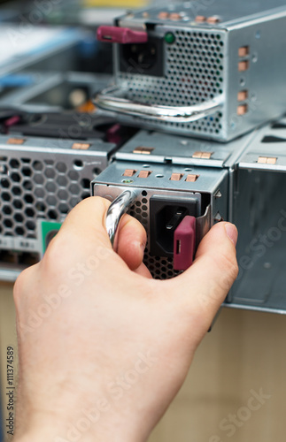 Computer technician installing power supply unit on server.