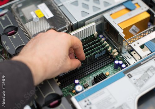 Computer technician installing RAM memory into motherboard.
