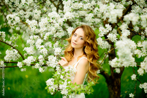 Spring beautiful girl, blonde, standing in a blooming Apple orchard .