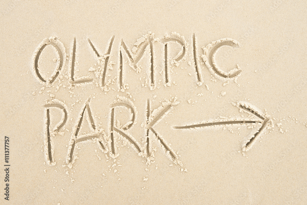 Handwritten message with arrow pointing the way to Olympic Park written in smooth sand Handwritten message with arrow pointing the way to Olympic Park written in smooth sand