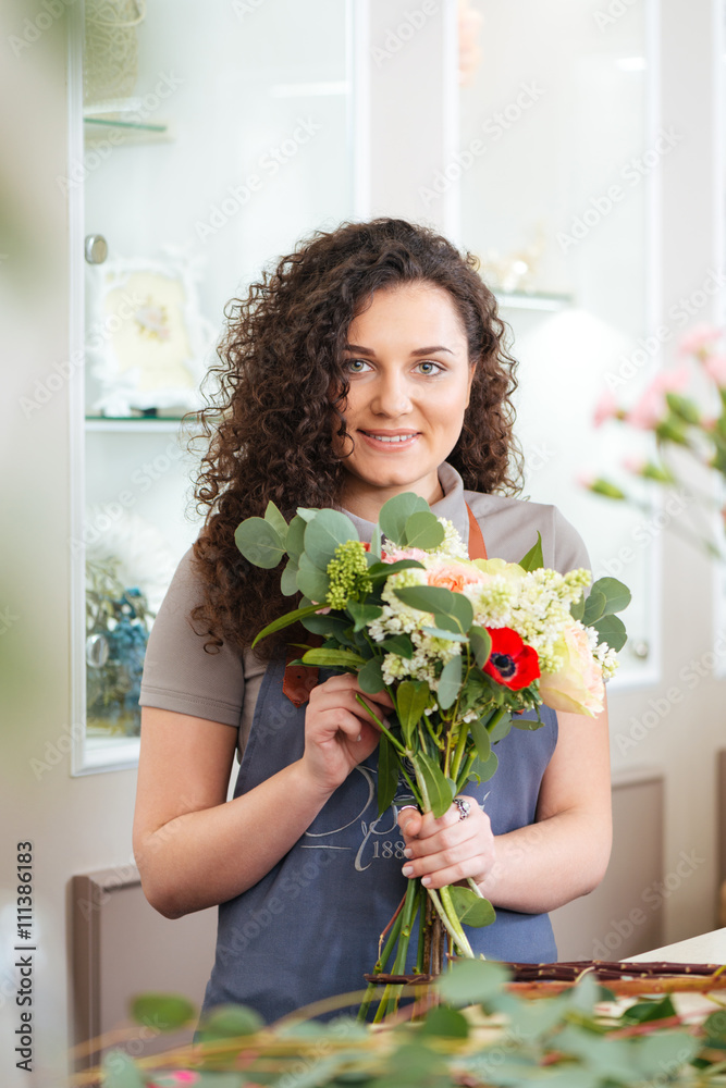 Smiling woman florist enjoying working in flower shop
