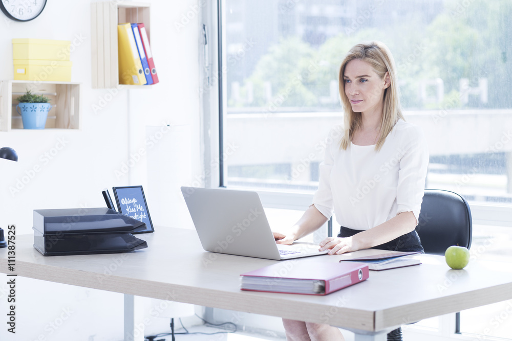 Beautiful blonde young business woman in office working on her laptop Beautiful blonde young business woman in office working on her laptop