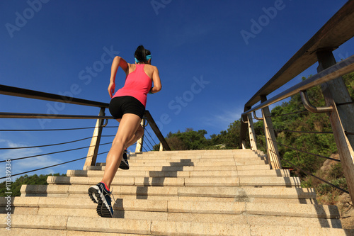 young fitness woman runner running on seaside stone stairs..