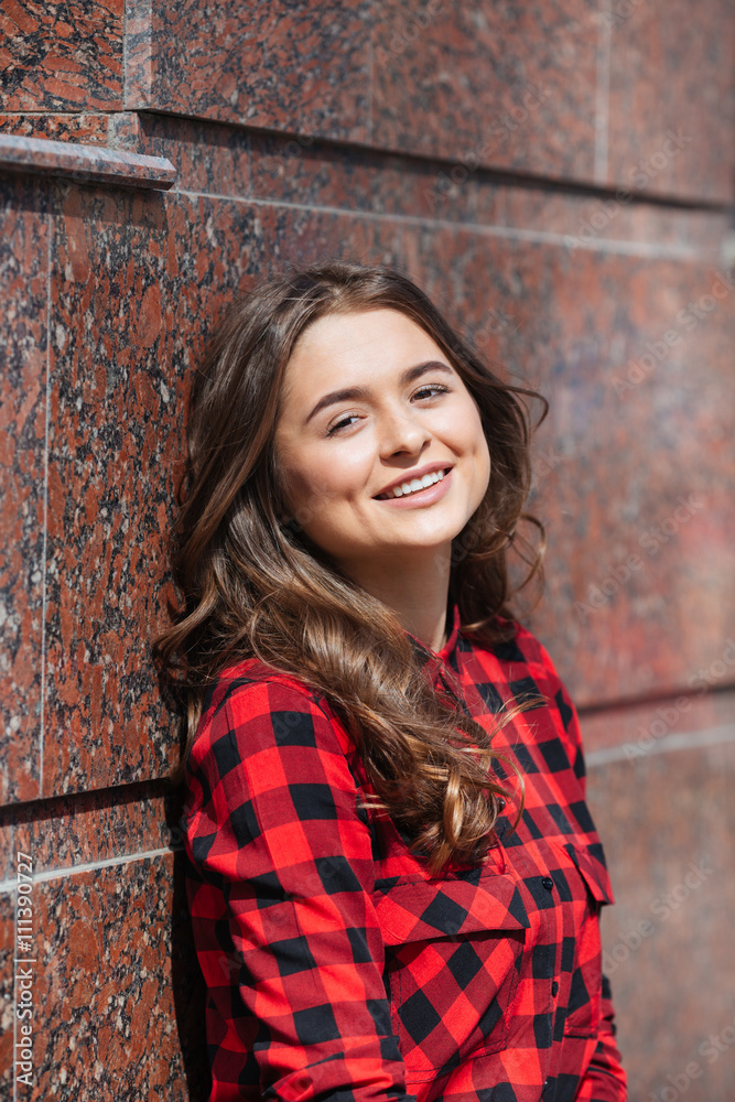 Smiling casual woman leaning on the wall