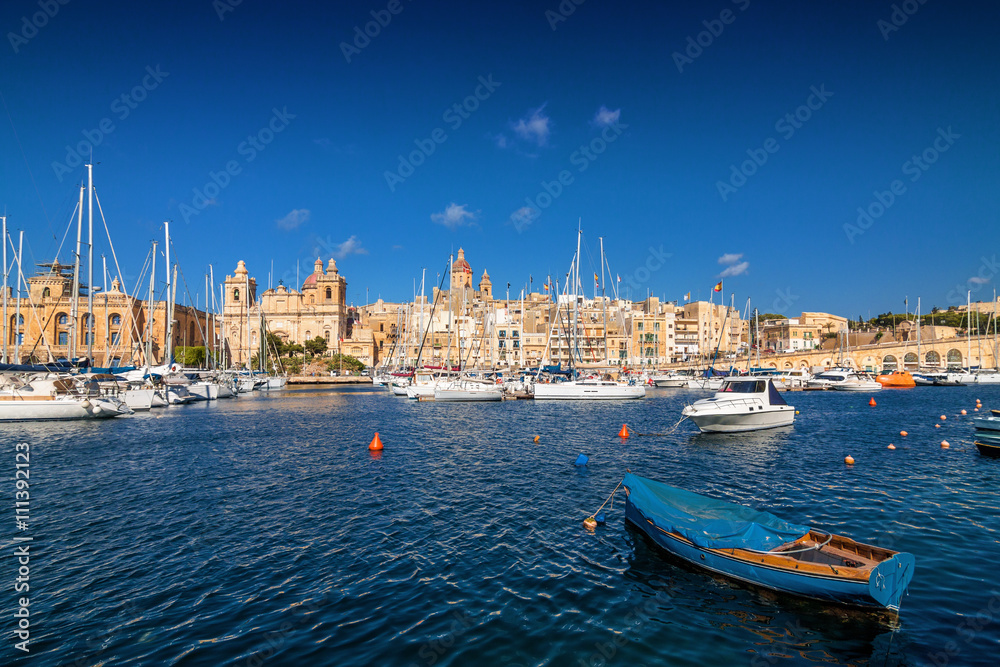 Sailboat on a background of yachts in the port of Valletta, Malta.