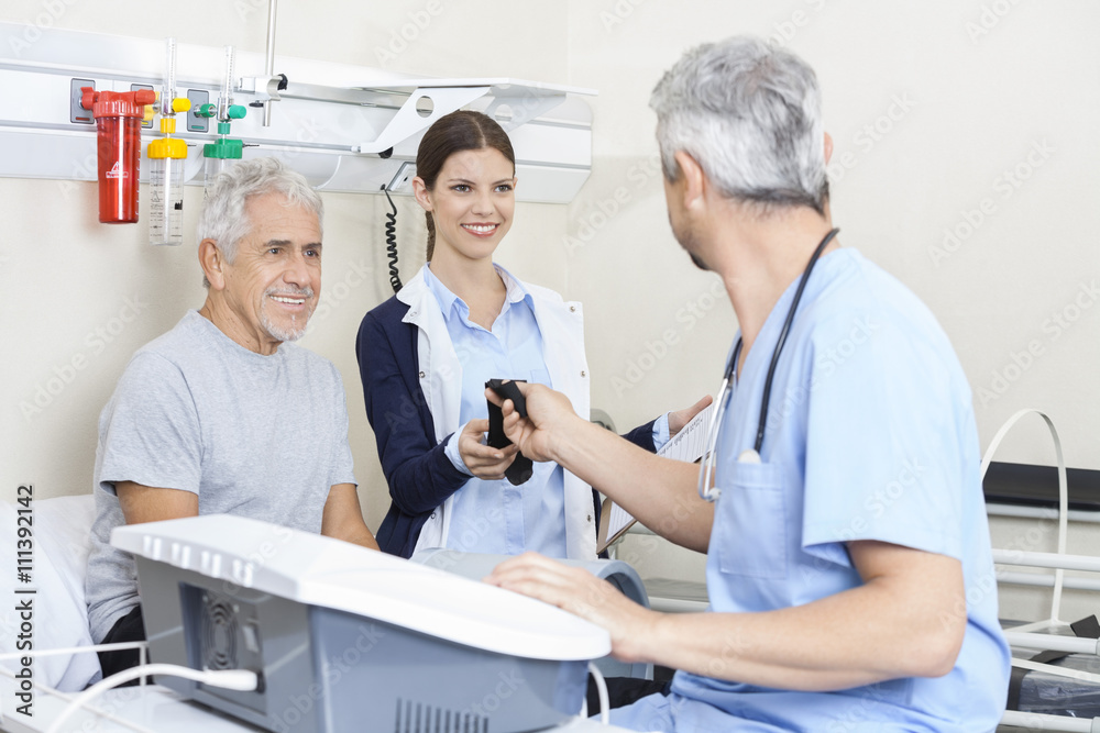 Obraz premium Physiotherapist Giving Belt To Colleague While Treating Senior M