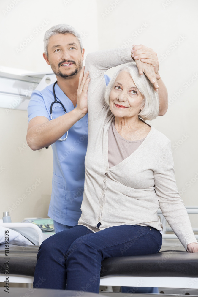 Obraz premium Physiotherapist Helping Senior Patient With Arm Exercise
