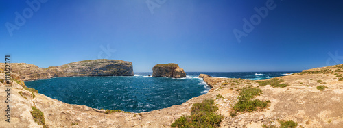 Sunny wide panoramic view of rocky Dweira bay in Gozo, Malta.