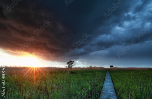 sunshine before rain storm over wooden path photo