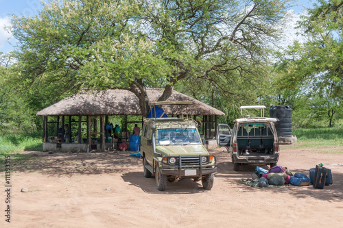 Tourist luggage and car in safari campsite (camp-lodge) in savanna. Serengeti National Park, Great Rift Valley, Tanzania, Africa. 