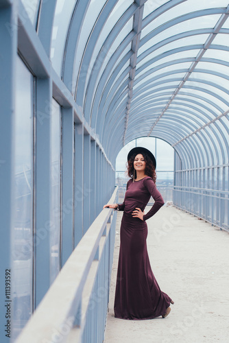 Beautiful curly-haired woman in a long dress on a light background