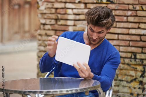 Young man using tablet pc as a mirror fixing hair photo