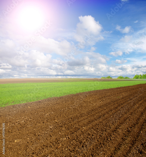 Beautiful spring landscape with plowed field under blue sky with clouds