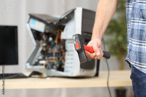 Hand holding a hammer after destroy a computer