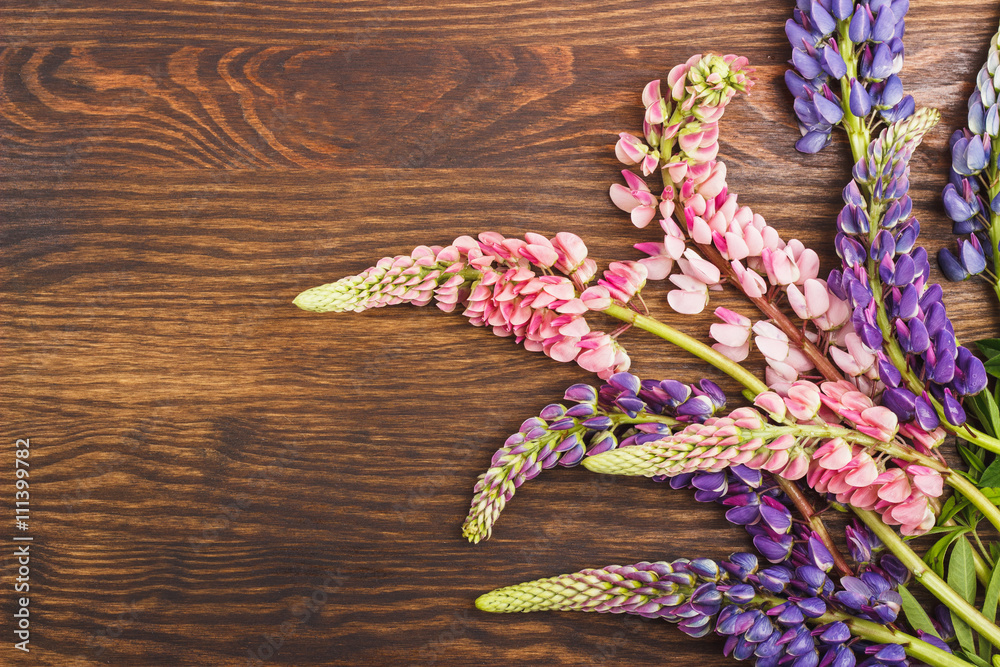 Naklejka premium Violet and pink lupinus on the wooden board
