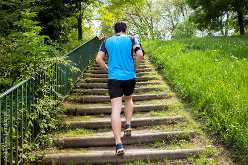 Close up of young man running up the stairs in a city park.Runner man Practice training on stairs in a city park.