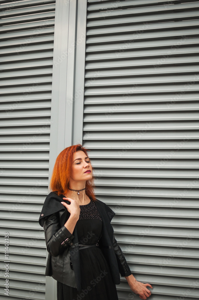 Fototapeta premium Style girl walks through the darl wall in black jacket and dress. Text place