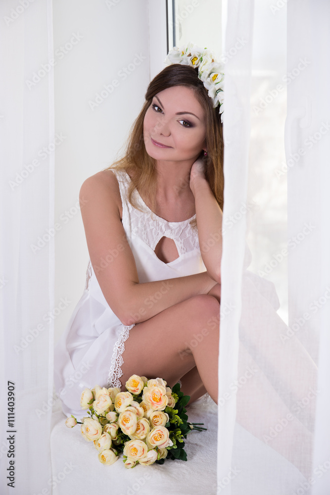 happy beautiful woman in white dress with flowers sitting near t happy beautiful woman in white dress with flowers sitting near t