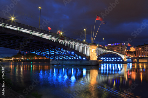 Cityscape: illuminated bridge over the Rhone river in Lyon at dusk.