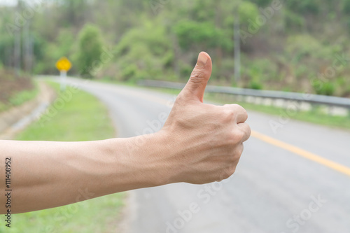 hand and hitchhiking sign on road