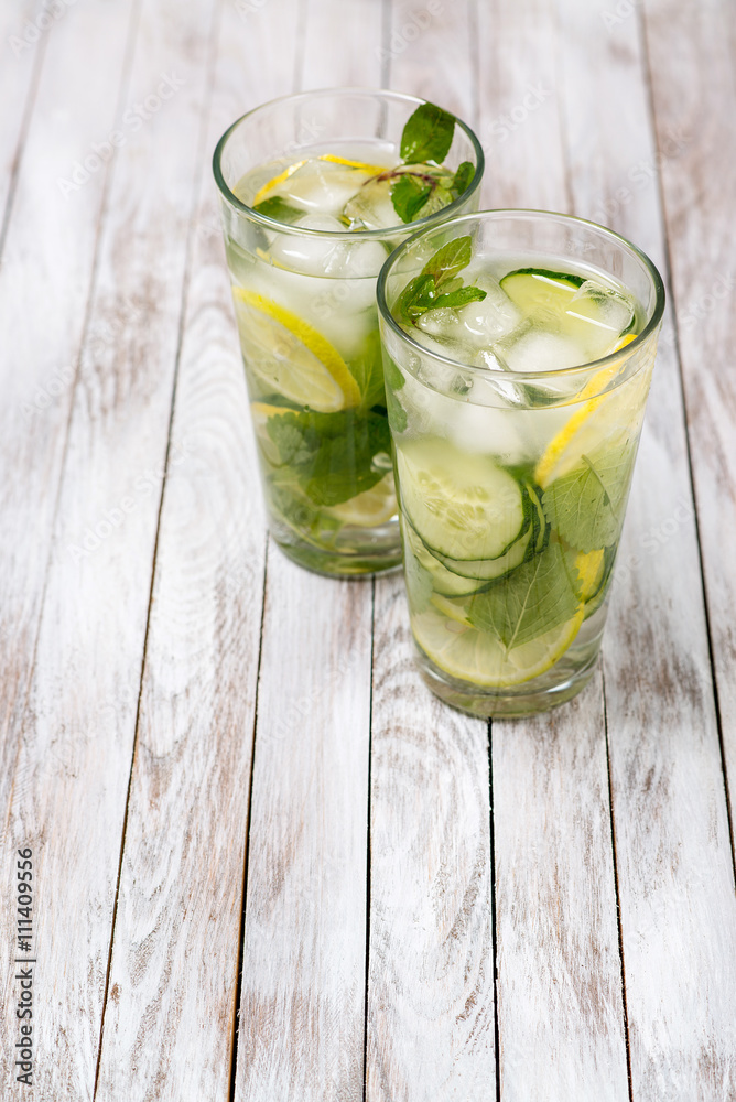 Water with lemon, mint and cucumber on wooden light background. Water Detox.