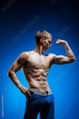 Fit young man with beautiful torso on blue background