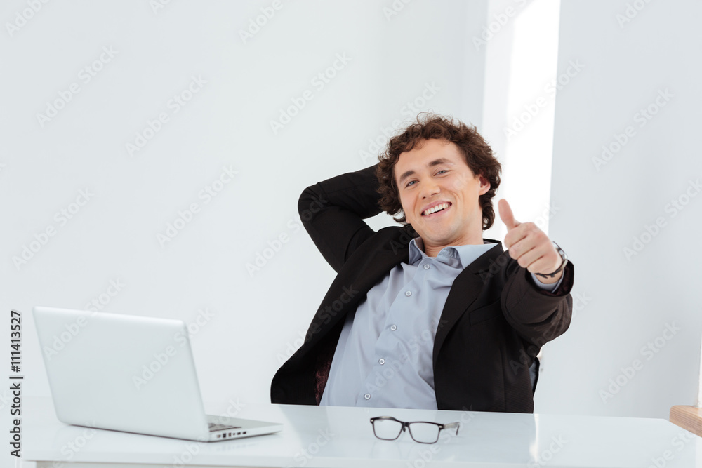 Businessman sitting at the table and showing thumb up Businessman sitting at the table and showing thumb up