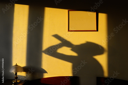 Cuadro en lienzo shadow of the alcoholic drinking from a bottle on a yellow wall