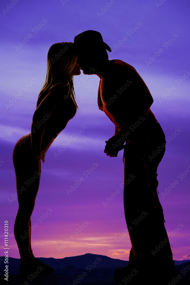 silhouette of a fit woman and cowboy kissing