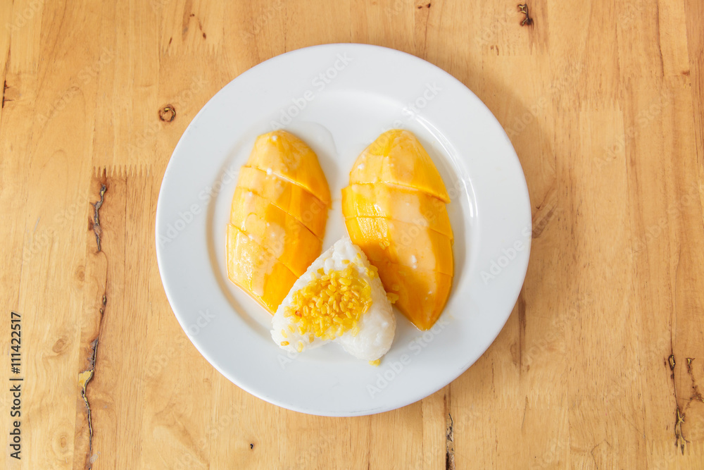 Mango sticky rice or khao niao mamuang is a Thai dessert made with glutinous rice on wood Mango sticky rice or khao niao mamuang is a Thai dessert made with glutinous rice on wood