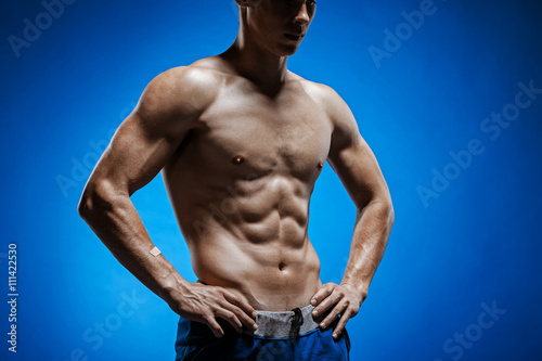 Fit young man with beautiful torso on blue background